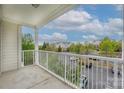 Condo balcony with white railing, overlooking a parking lot and landscaped grounds with trees at 11544 Costigan Ln # 8306, Charlotte, NC 28277