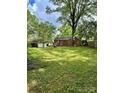 Large grassy backyard featuring mature trees and a storage shed, offering privacy at 3507 Rogers St, Charlotte, NC 28208