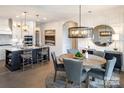 Open-concept dining area featuring a wooden table set for six, a decorative mirror, and stylish pendant lighting fixtures at 4825 Reason Ct # 73, Harrisburg, NC 28075