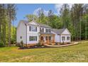 Elegant two-story home featuring manicured lawn and lush greenery, set against a backdrop of mature trees at 545 Morrison Farm Rd, Troutman, NC 28166