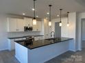 Modern kitchen featuring a large island with black countertops, stainless steel appliances, and pendant lighting at 6333 Honor Ave, Midland, NC 28107