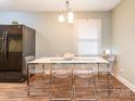 Bright dining room with modern table and chairs, black refrigerator, light fixture, and wood floors at 905 Mount Olivet Rd, Kannapolis, NC 28083
