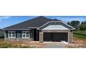 New construction exterior features a two-car garage with a stone facade and gray siding accents at 1030 Gardenia Dr # 2, Mt Ulla, NC 28125