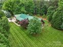 An aerial view of a beautiful log home with green roof and large manicured lawn at 10583 Earnhardt Lake Rd, Davidson, NC 28036