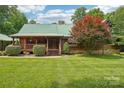 Inviting log home with a covered front porch, manicured lawn, and lovely landscaping at 10583 Earnhardt Lake Rd, Davidson, NC 28036