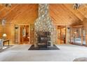 Open-concept living room showcasing a striking stone fireplace, wood-paneled walls, and hardwood flooring at 10583 Earnhardt Lake Rd, Davidson, NC 28036