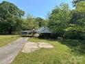 Quaint, overgrown exterior with an attached carport, concrete front, and mature trees, perfect for renovation at 191 S Main St, Richburg, SC 29729