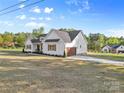 View of home featuring two-car attached garage, professional landscaping, and white siding at 215 Scout Rd, Locust, NC 28097