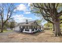 Side view of a white house with a covered porch and mature trees in a spacious yard at 221 Palmer St, Albemarle, NC 28001