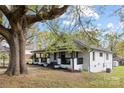 A charming white house is nestled beneath a tree with fresh landscaping and a inviting porch at 221 Palmer St, Albemarle, NC 28001