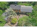 Beautiful aerial view showcasing the brick home, lush landscaping, and expansive lot surrounded by trees at 3232 Kale Ln, Matthews, NC 28105