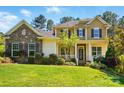 Inviting two-story home featuring stone and siding, a well-kept lawn, and mature landscaping at 404 Brookridge Dr, Mount Holly, NC 28120