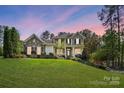 Two-story home with a stone facade, shutters, landscaped yard, and inviting front porch at dusk at 404 Brookridge Dr, Mount Holly, NC 28120