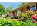 A beautiful brick house with colorful flowers, shrubs, and mature trees on a sunny day at 4925 Seacroft Rd, Charlotte, NC 28210
