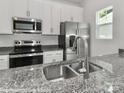 Close-up of a kitchen with granite countertops, a stainless steel sink, and appliances at 556 Ridge Ave, Mooresville, NC 28115