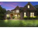 Elegant brick home at twilight, showcasing illuminated windows and lush landscaping at 7600 Brookmont Ln, Waxhaw, NC 28173