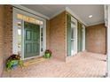 Inviting brick front porch with a green door, shutters, and potted plants at 7600 Brookmont Ln, Waxhaw, NC 28173