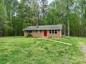 A quaint brick house with a red front door is framed by tall trees and a well-kept lawn at 181 Canipe Rd, Dallas, NC 28034