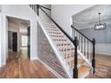 Staircase with decorative accent wall, hardwood floors, and black and white railing providing an eye-catching foyer design at 1811 Robbins Meadows Dr, Waxhaw, NC 28173