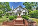 Traditional white home with brick stairs leading to the front door, surrounded by lush green landscaping at 2101 Dilworth W Rd, Charlotte, NC 28203