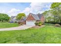 Beautifully landscaped yard surrounds this charming brick home with an expansive green lawn at 2104 Planters Knoll Dr, Monroe, NC 28110