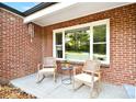 Inviting front porch area featuring two rocking chairs, brick walls, and a view of the landscaped yard at 2121 Arnold Dr, Charlotte, NC 28205