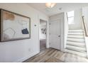 Hallway with wood-look floors leading to stairs, a doorway, and neutral wall art at 2124 Barrowcliffe Nw Dr, Concord, NC 28027