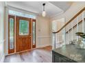 Foyer with a hardwood floor, stained glass sidelights, elegant pendant light, and staircase at 2221 Hamilton Mill Rd, Charlotte, NC 28270