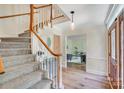 Foyer features staircase, hardwood floor, stylish gray cabinet, pendant light, and home office view at 2221 Hamilton Mill Rd, Charlotte, NC 28270