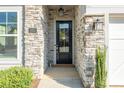 Close-up of the front door with stone surround, modern light fixtures, and clear address numbers at 3012 Laney Pond Rd, Matthews, NC 28104