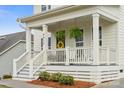 Inviting front porch featuring rocking chairs, ferns, yellow wreath and classic white railings and columns at 4012 Spring Cove Way, Belmont, NC 28012