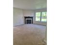 Inviting living room with a cozy fireplace, plush carpet and bright natural light through the large windows at 7113 Sycamore Grove Ct, Charlotte, NC 28227