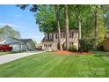 A two-story home with red shutters, a long driveway, and a detached garage in a leafy setting at 7220 Spring Morning Ln, Charlotte, NC 28227