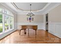 Elegant dining room with a grand piano, chandelier, and ample natural light at 914 Elizabeth Ln, Matthews, NC 28105
