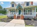 Inviting front porch with brick steps, hanging plants, rocking chairs, and a teal front door at 1228 Quiet Acres Rd, Rock Hill, SC 29732
