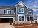 Two story home with blue siding, brick base, and white trim against a partly cloudy sky at 13304 Chopin Ridge Dr, Huntersville, NC 28078