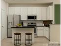 Bright kitchen with white cabinets, stainless steel appliances, a center island with seating, and black countertops at 4539 Potters Wheel Dr, Fort Mill, SC 29715