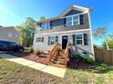 Charming two-story home with grey siding, black shutters, and inviting wooden steps to the front door at 606 E Carpenter St, Dallas, NC 28034