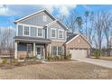 Charming two-story home featuring blue siding, brick accents, and a welcoming front porch with seating at 1043 Kalli Dr, Matthews, NC 28104