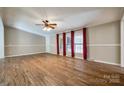 Bright, open living room with hardwood floors, ceiling fan, and large windows dressed with red drapes at 1060 Sierra Rd, York, SC 29745