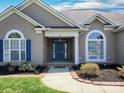 Inviting home entrance with blue door, brick accents, arched windows, and landscaped flowerbeds at 126 Dairy Farm Rd, Mooresville, NC 28115