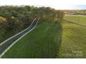 Scenic aerial view of a long driveway leading to horse farm with fenced pastures and lush green landscape at 15670 Bethel Avenue Ext, Midland, NC 28107