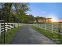 The long paved driveway is flanked by a white fence, leading to the main house on the farm at 15670 Bethel Avenue Ext, Midland, NC 28107