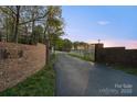 Farm entrance featuring brick columns with decorative gates, a sign, and a long driveway at 15670 Bethel Avenue Ext, Midland, NC 28107