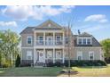 Charming two-story home featuring a covered front porch, upper balcony and well-manicured lawn at 164 Riverstone Dr, Davidson, NC 28036