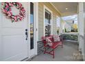 Cozy front porch seating with a red bench, decorative pillows, and an inviting view of the neighborhood at 164 Riverstone Dr, Davidson, NC 28036