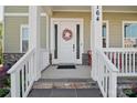 Inviting covered front porch with white columns and railings, featuring a decorative floral wreath on the front door at 164 Riverstone Dr, Davidson, NC 28036