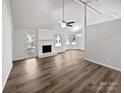 Spacious living room featuring wood-look flooring, a white brick fireplace, and access to the back patio at 1727 Running Brook Rd, Charlotte, NC 28214