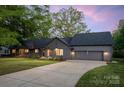Twilight view of gray single-story home with a well-manicured lawn, attached garage, and inviting front entrance at 235 Commodore Loop, Mooresville, NC 28117