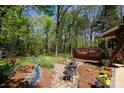 Landscaped backyard featuring a stone pathway, patio seating, flower beds, and a wooden deck at 4289 Falcon Hall Way, Rock Hill, SC 29730